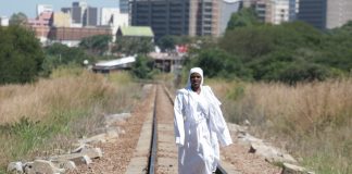 An Apostolic woman walks along train tracks on her way back from a mountain prayer session.