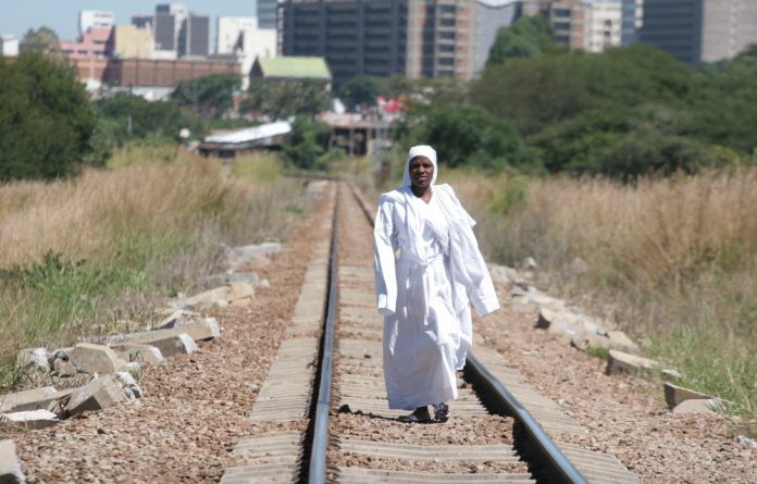 An Apostolic woman walks along train tracks on her way back from a mountain prayer session.