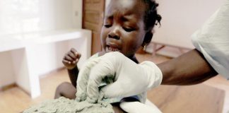 A nurse treats a young patient's buruli ulcer with a clay poultice.