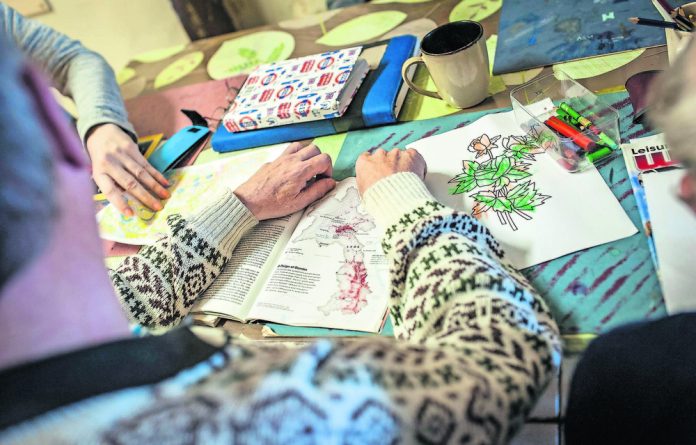 Some lower functioning Care Haven Psychiatric Centre residents are guided through drawing and reading with a staff member as part of a daily programme to keep them active