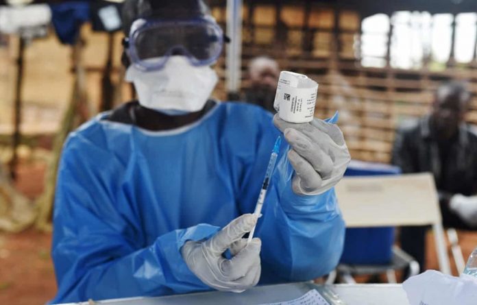 A health worker prepares to administer Ebola vaccine outside a house in the village of Mangina