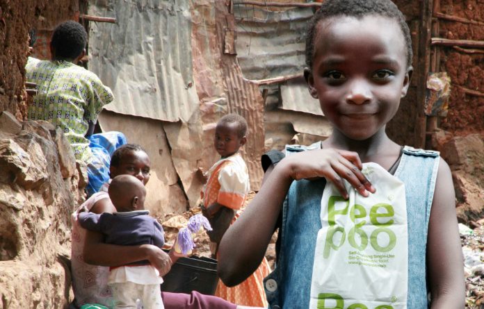 A girl in Kibera holds up the Peepoo