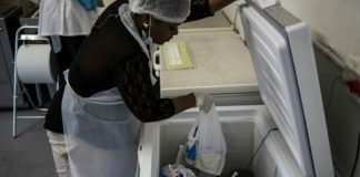 A worker pulls donations from a fridge at a breast milk bank. As of May