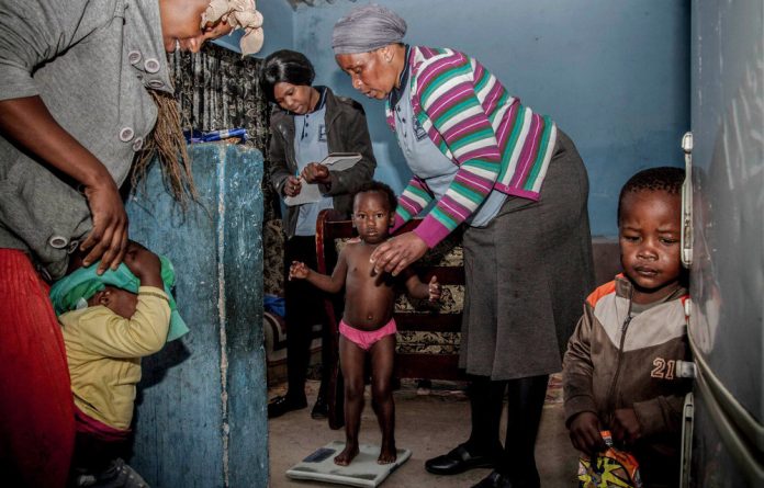 Home care: Community healthworker Nonqaba Melani weighs a child in Khayelitsha