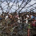 No man’s land: People gather behind a barbed wire fence in a temporary settlement on the Myanmar border. When governments fail, aid organisations step in. But who should they report to? (Ye Aung Thu, AFP)