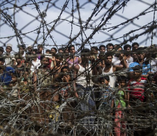 No man’s land: People gather behind a barbed wire fence in a temporary settlement on the Myanmar border. When governments fail, aid organisations step in. But who should they report to? (Ye Aung Thu, AFP)
